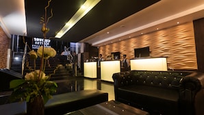 A modern hotel lobby with a reception desk, a black leather sofa, and a staircase. - Clover Suites Royal Lake Yangon (Yangon)