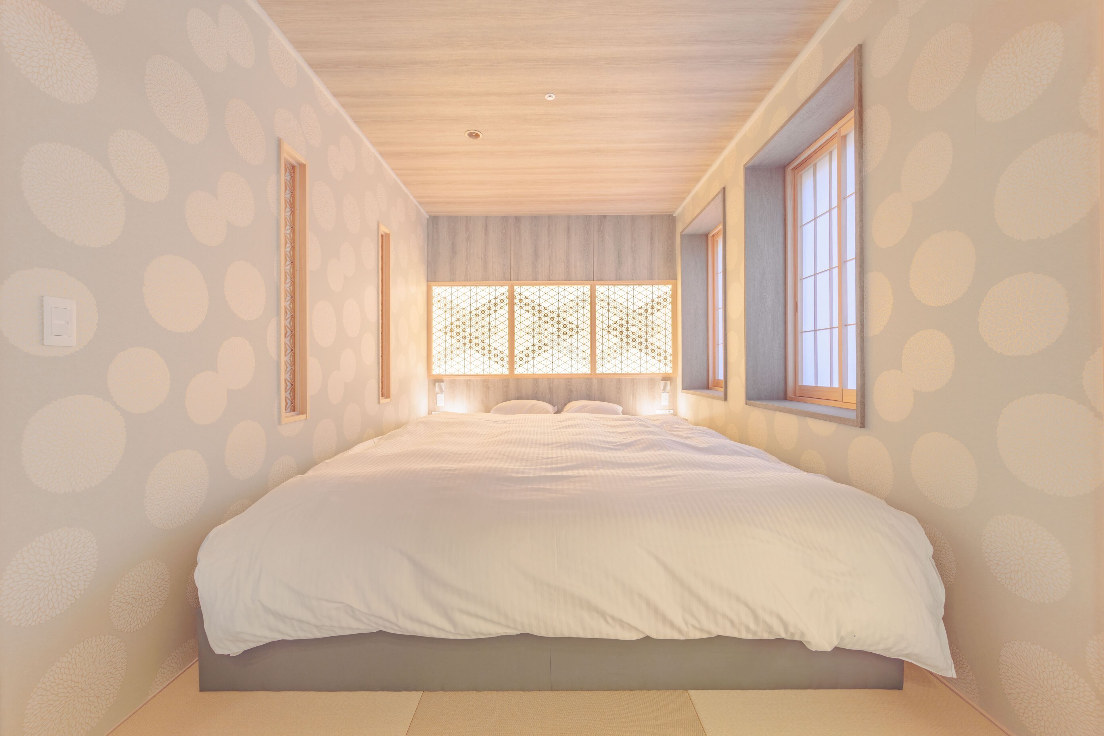 A bedroom with a large bed, a window with a view, and a patterned wall.