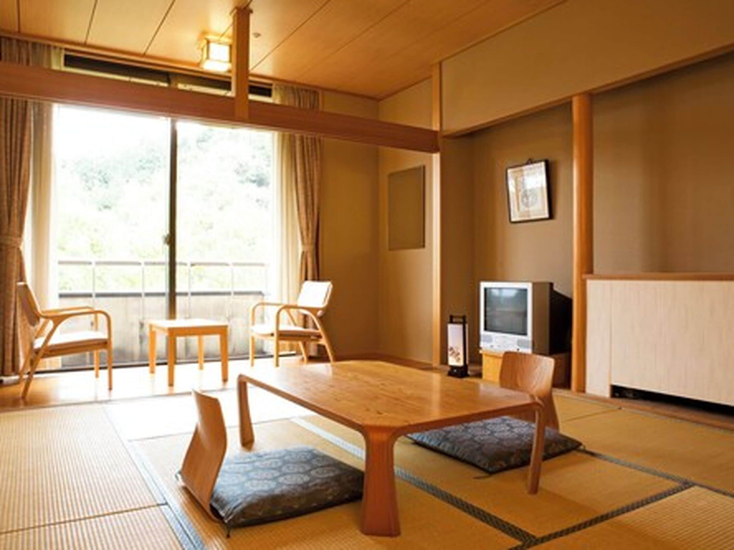 A traditional Japanese room with tatami flooring, a low table, and two chairs.