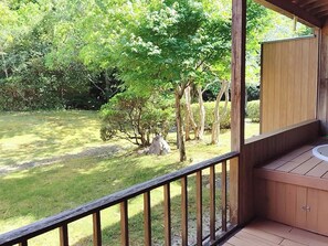 Una terraza de madera con un jacuzzi y vistas a un jardín con árboles.