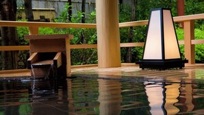A tranquil indoor pool area with a wooden deck, a small waterfall feature, and a traditional-style lamp. - Sennomori (Ise)