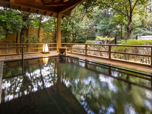 Una piscina interior tranquila con una cubierta de madera y una valla de bambú.
