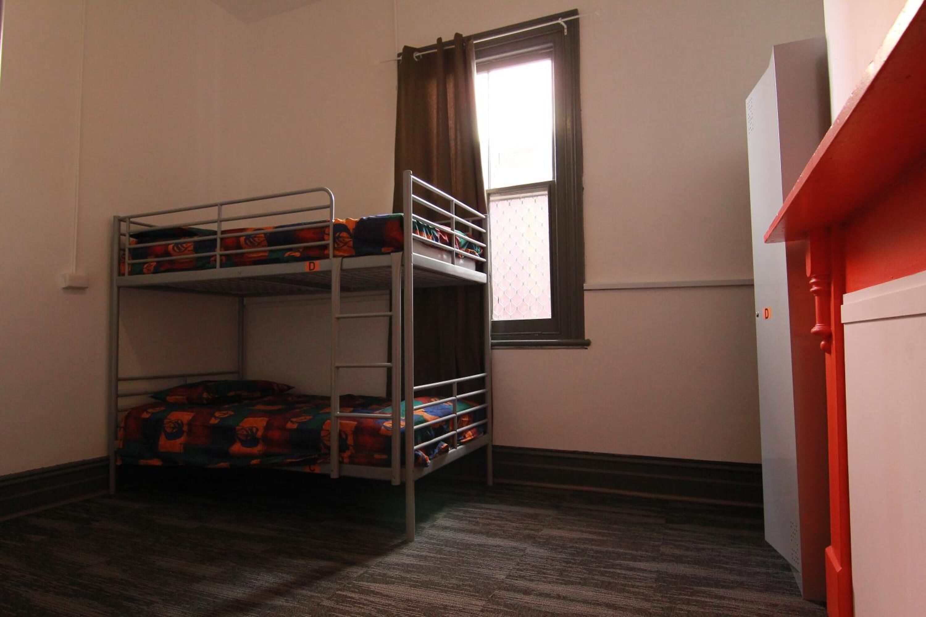 Habitación con literas, piso alfombrado y puerta blanca.