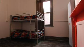 Habitación con literas, piso alfombrado y puerta blanca.