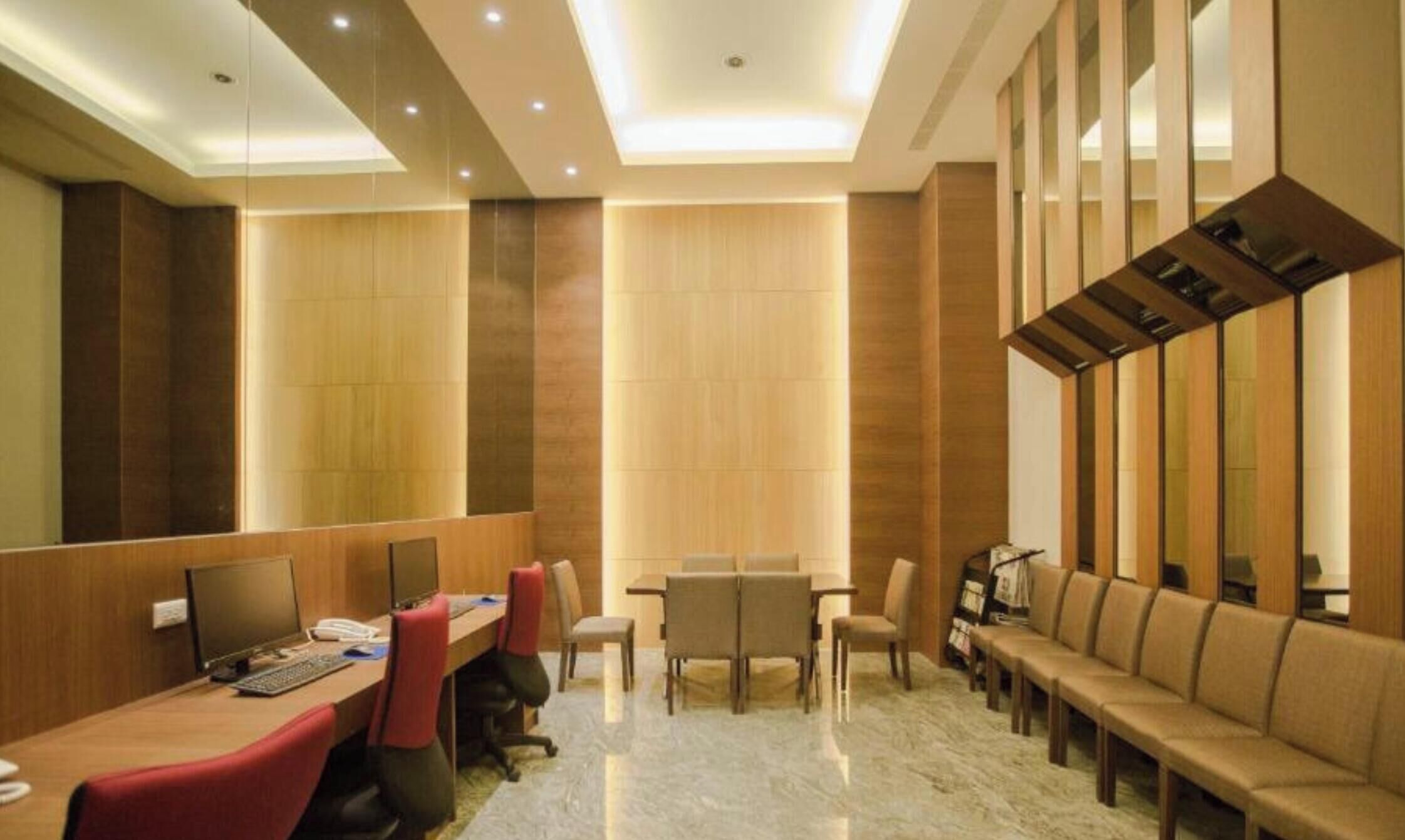 Un salón de conferencias con una larga mesa, múltiples sillas, un sofá y una pantalla de televisión.