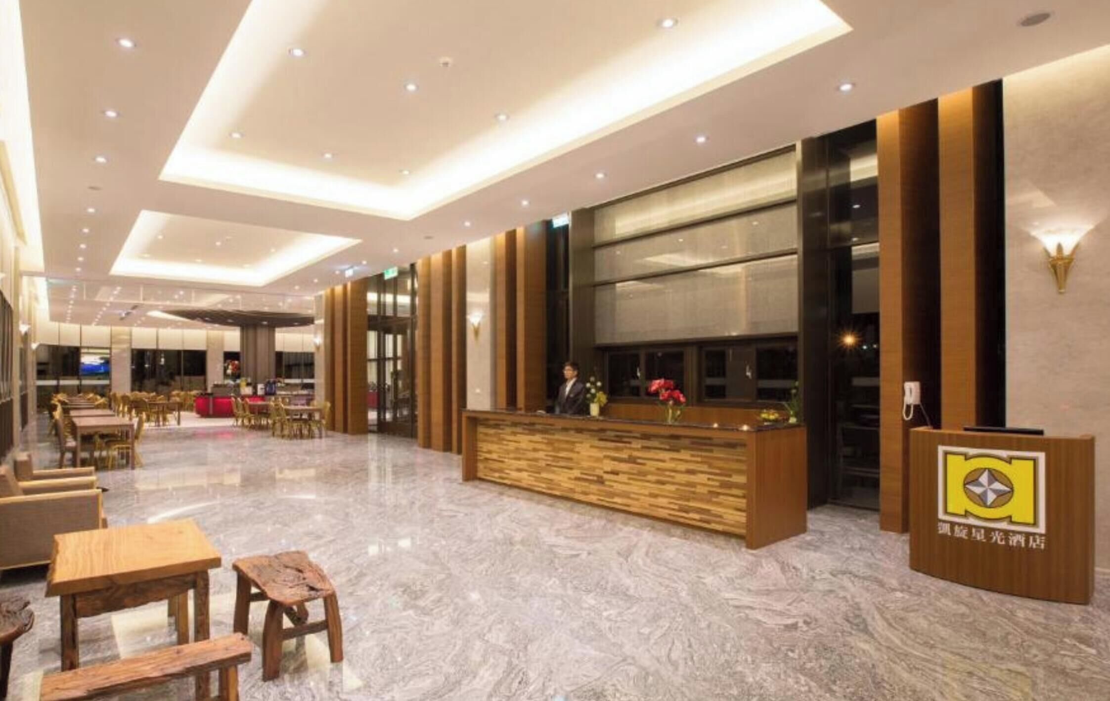 A hotel lobby with a reception desk, seating area, and a large window.