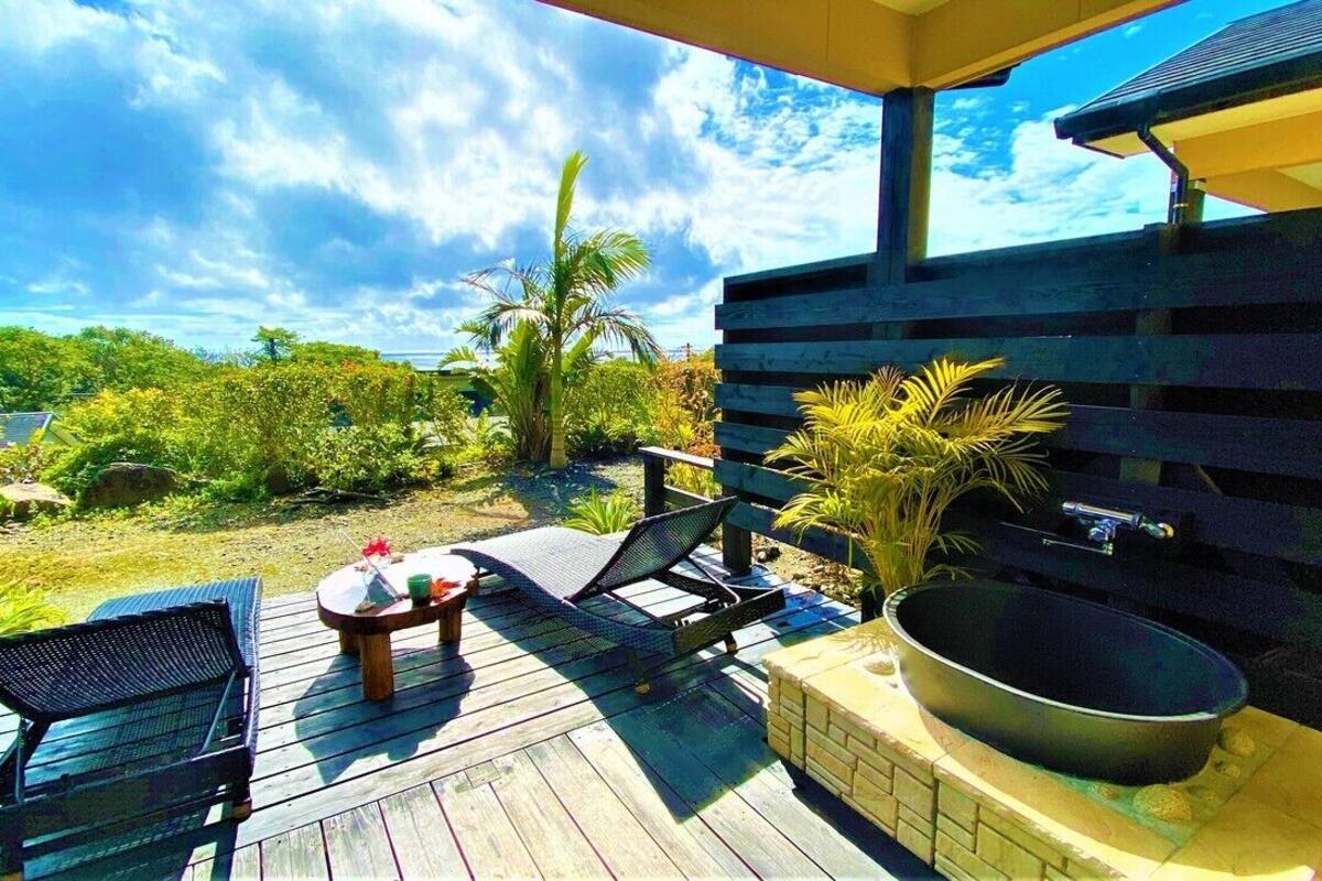 A wooden deck with lounge chairs, a table, and a hot tub.