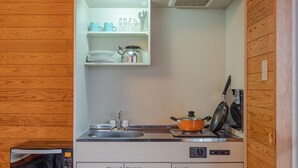 Een kleine keuken met een magnetron, fornuis, spoelbak en kastjes.