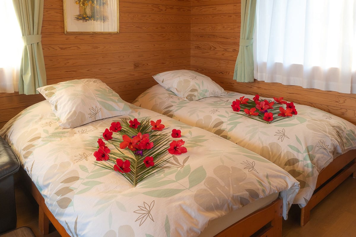 A double bed with floral bedding and a bouquet of red flowers on the center.