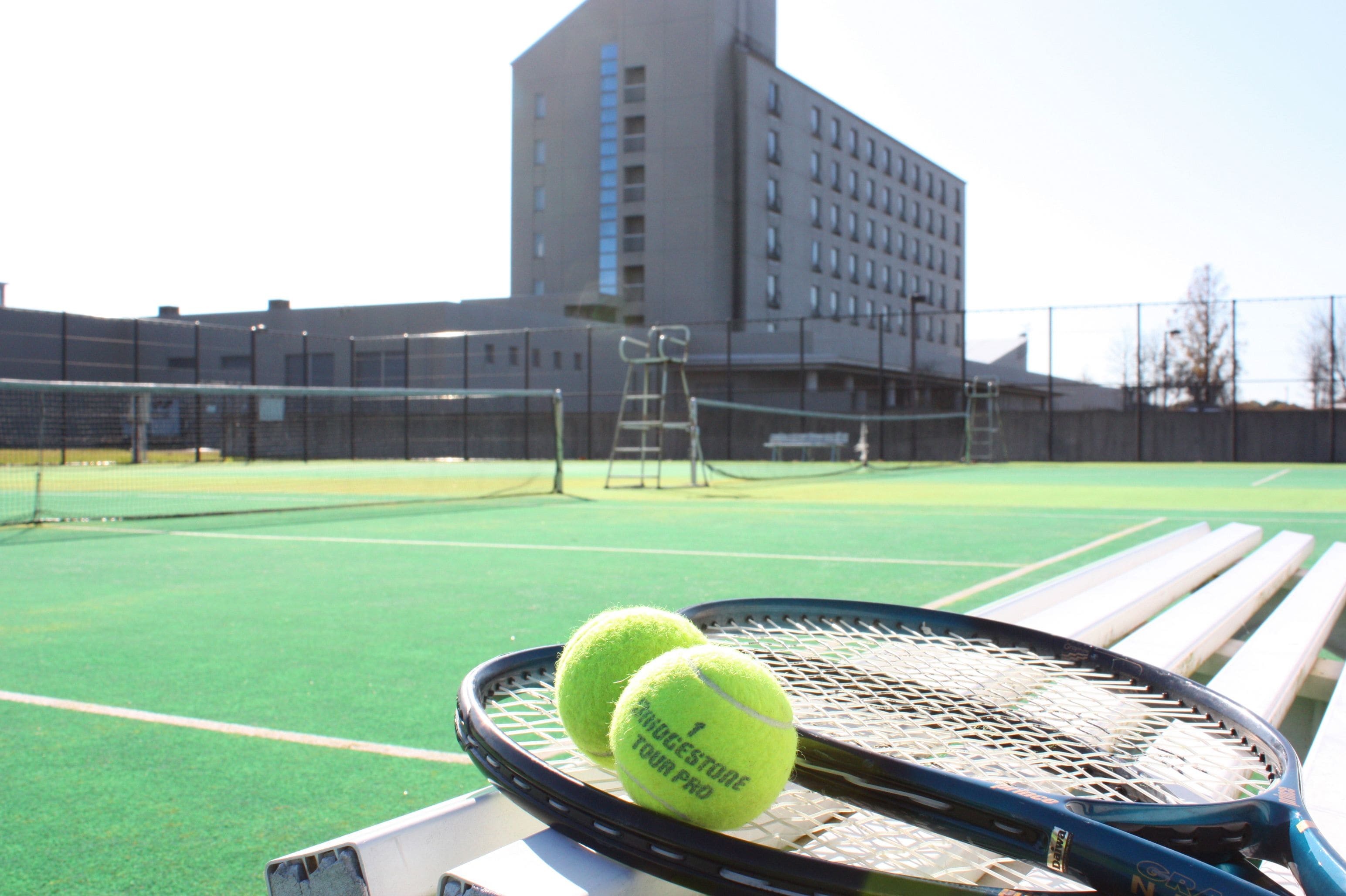 Ein Tennisplatz mit zwei Tennisbällen und einem Schläger auf einer Bank.