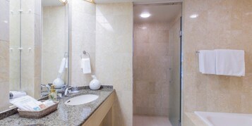 A modern bathroom with a granite countertop, a sink, a glass shower enclosure, and a bathtub.