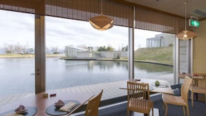A dining area with a view of a lake and modern buildings. - Hotel Arrowle (Kaga)