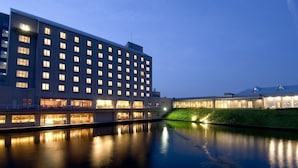 A modern hotel with multiple floors, a reflective pool, and a well-lit exterior. - Hotel Arrowle (Kaga)