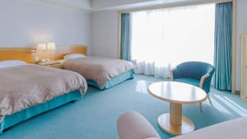 A hotel room with two beds, a round table, a chair, and a wardrobe.
