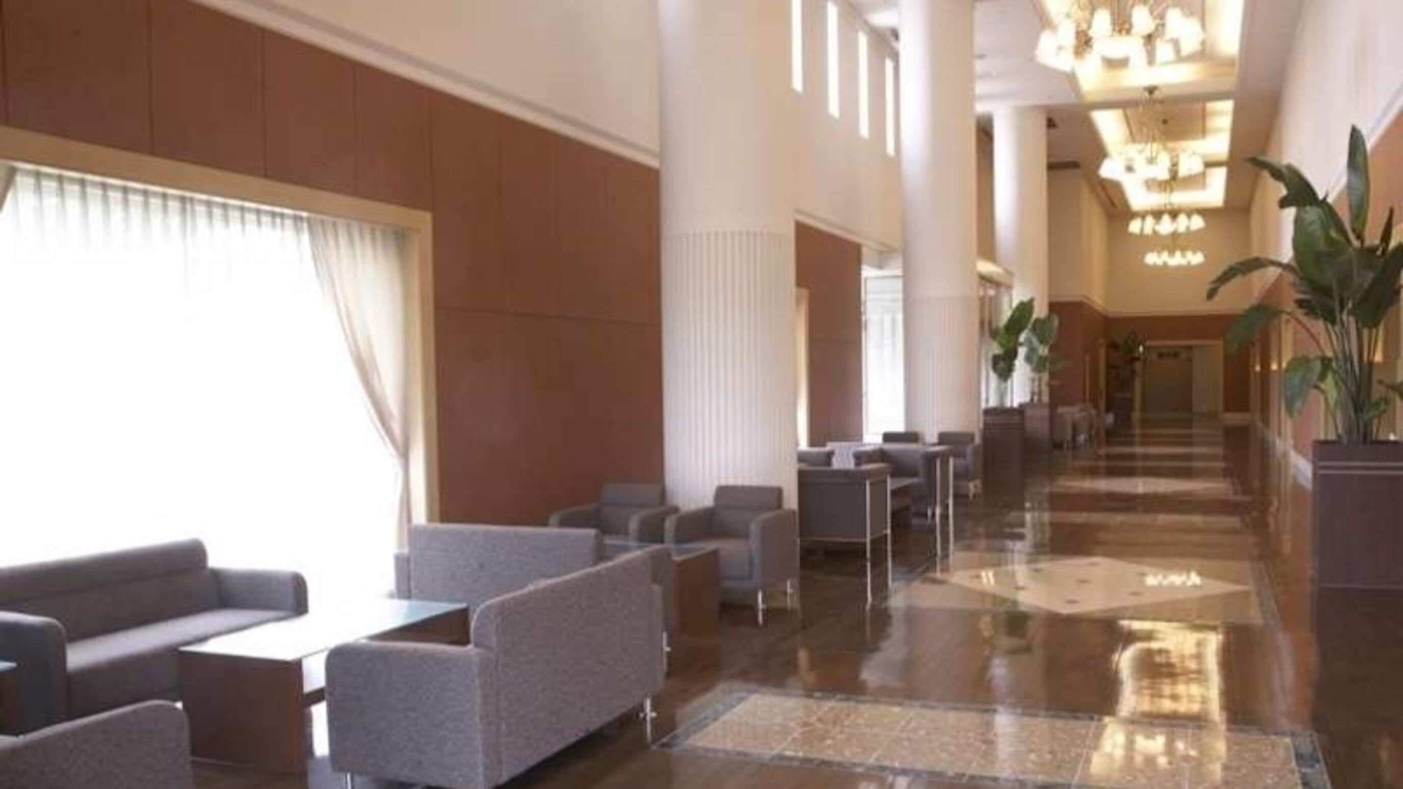 Un hall amplio con piso pulido, zonas de estar y una escalera imponente.