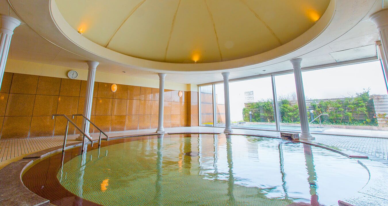 An indoor swimming pool with a tiled floor, a glass wall, and a ceiling with lights.