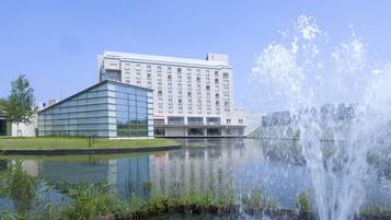 A modern hotel with a glass facade and a water feature in front.