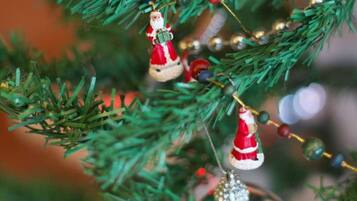 A close-up of a Christmas tree with ornaments, including a Santa Claus figure and a beaded ornament.