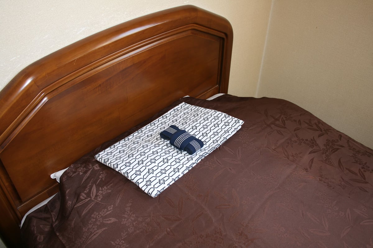 Un lit avec une tête de lit marron et un coussin à motifs.