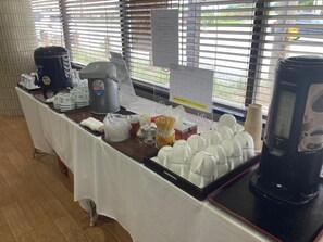 Un buffet avec des machines à café, des gobelets jetables et un plateau rempli de bols blancs.