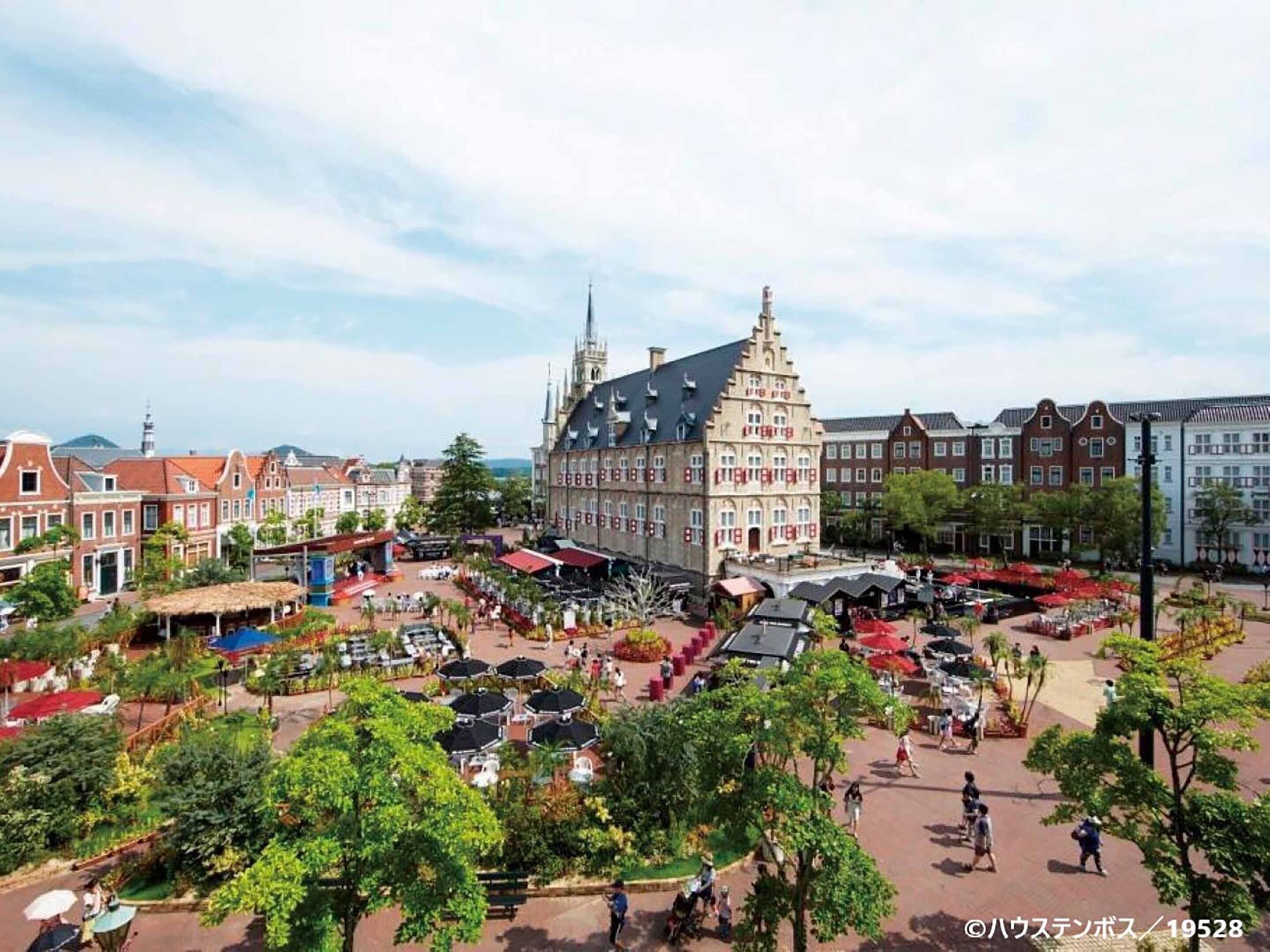A historic building with a prominent tower and a courtyard with outdoor seating and greenery.