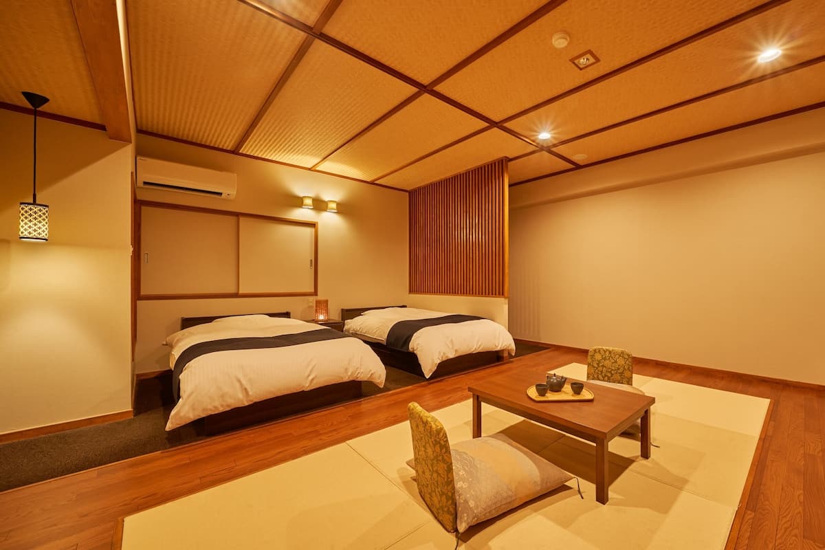 A traditional Japanese-style bedroom with two beds, a wooden table, and tatami mats.