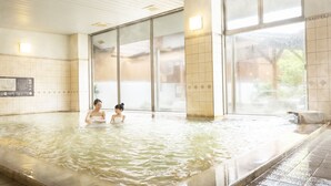 A large indoor swimming pool with clear water, tiled walls, and large windows.
