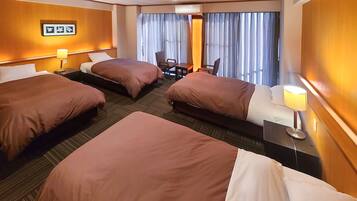 A hotel room with three beds, a desk, and a chair.
