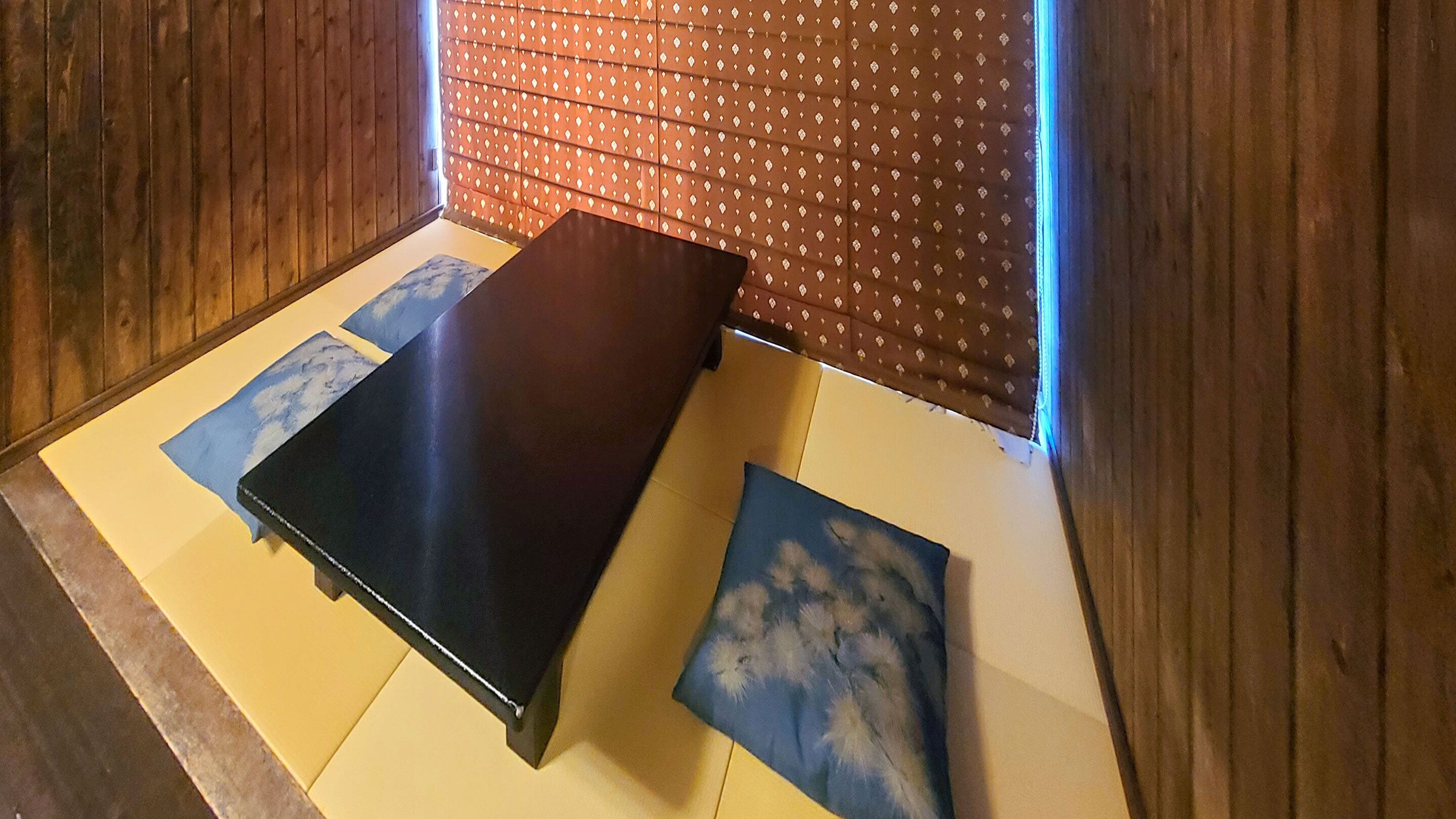 A room with a wooden floor, a dark-colored bed, and a patterned wall.