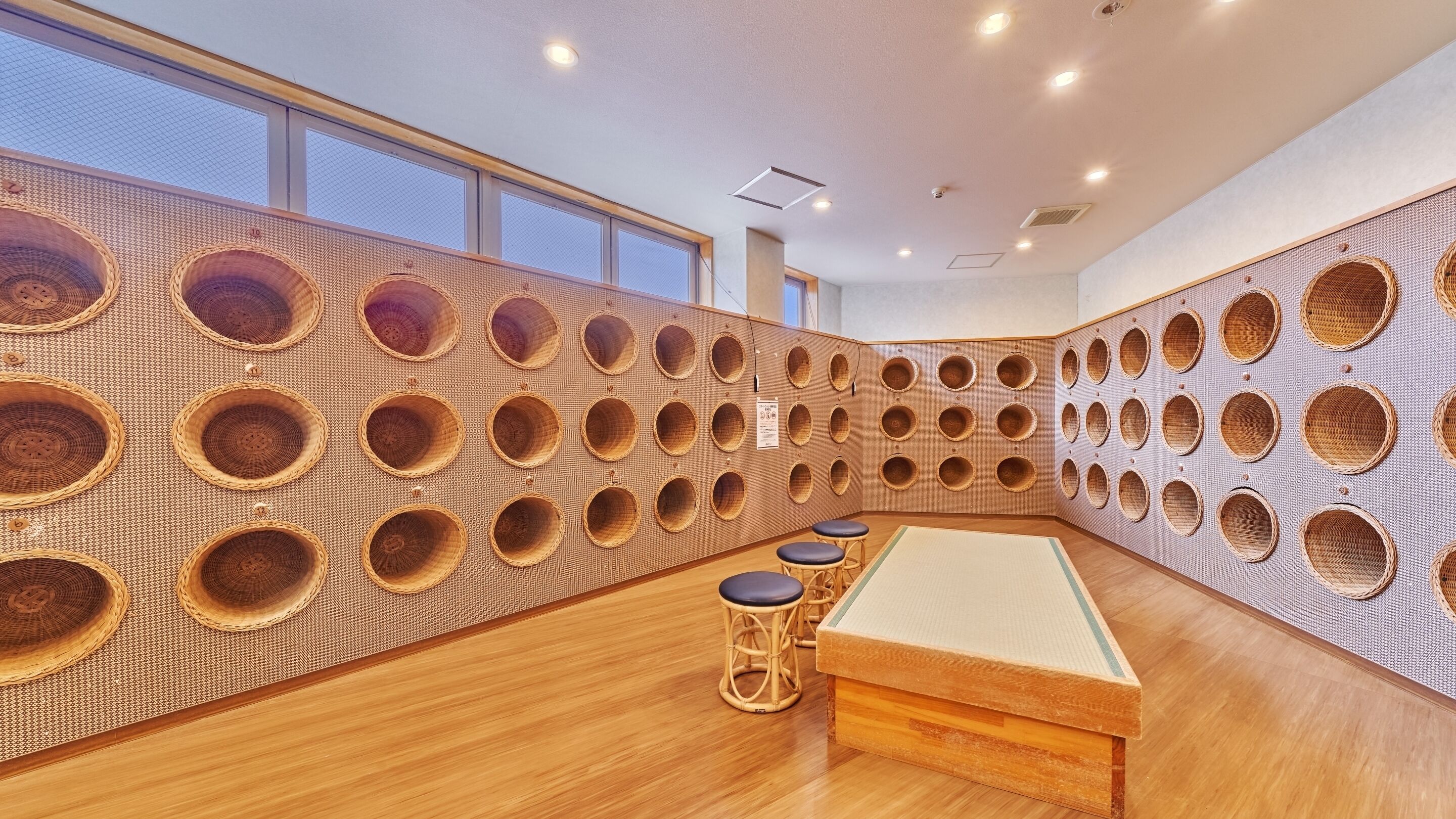 A room with a unique wall design featuring circular cutouts, a pool table, and wooden flooring.