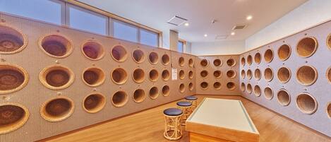 A room with a unique wall design featuring circular cutouts, a pool table, and wooden flooring.