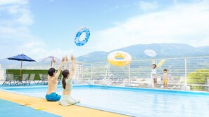 Ein Schwimmbecken mit Blick auf Berge, Liegestühle und Sonnenschirme.