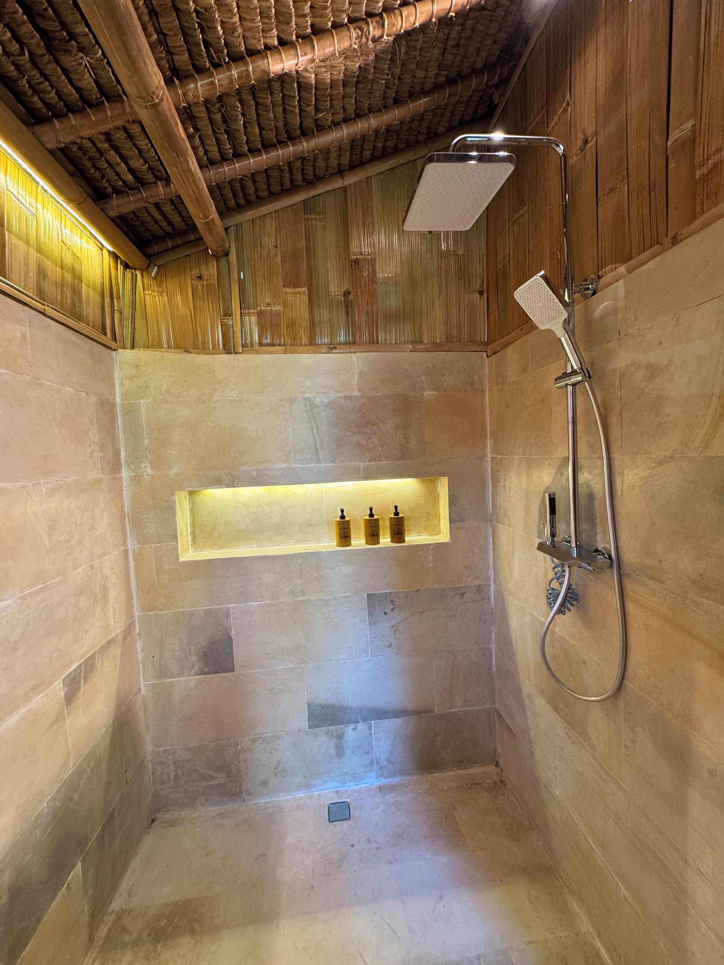 A shower area with a built-in shelf, a handheld showerhead, and a drain.