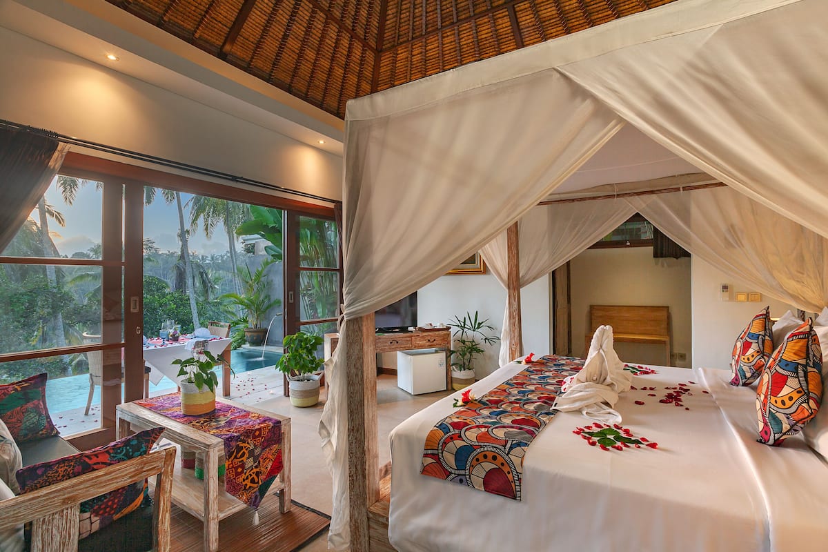 A spacious room with a large bed, a dining area, and a view of the outdoors.