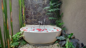 Un bain  à remous entouré de plantes et bordé d’un mur en pierre.