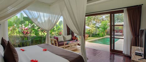 Een slaapkamer met een bed, uitzicht op een zwembad en een balkon met tuinmeubilair.