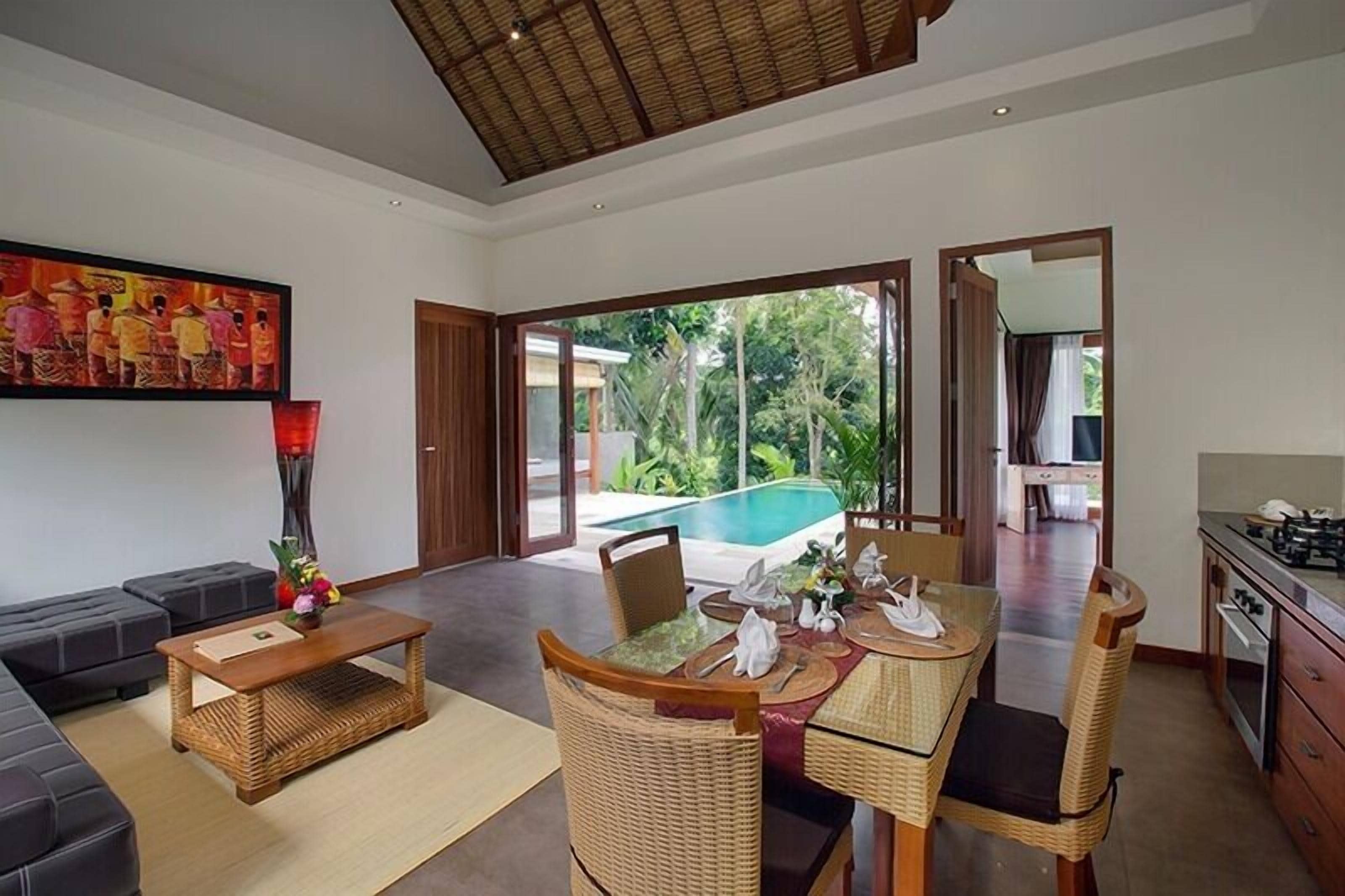 A spacious living area with a dining table, comfortable seating, and a view of an outdoor swimming pool.