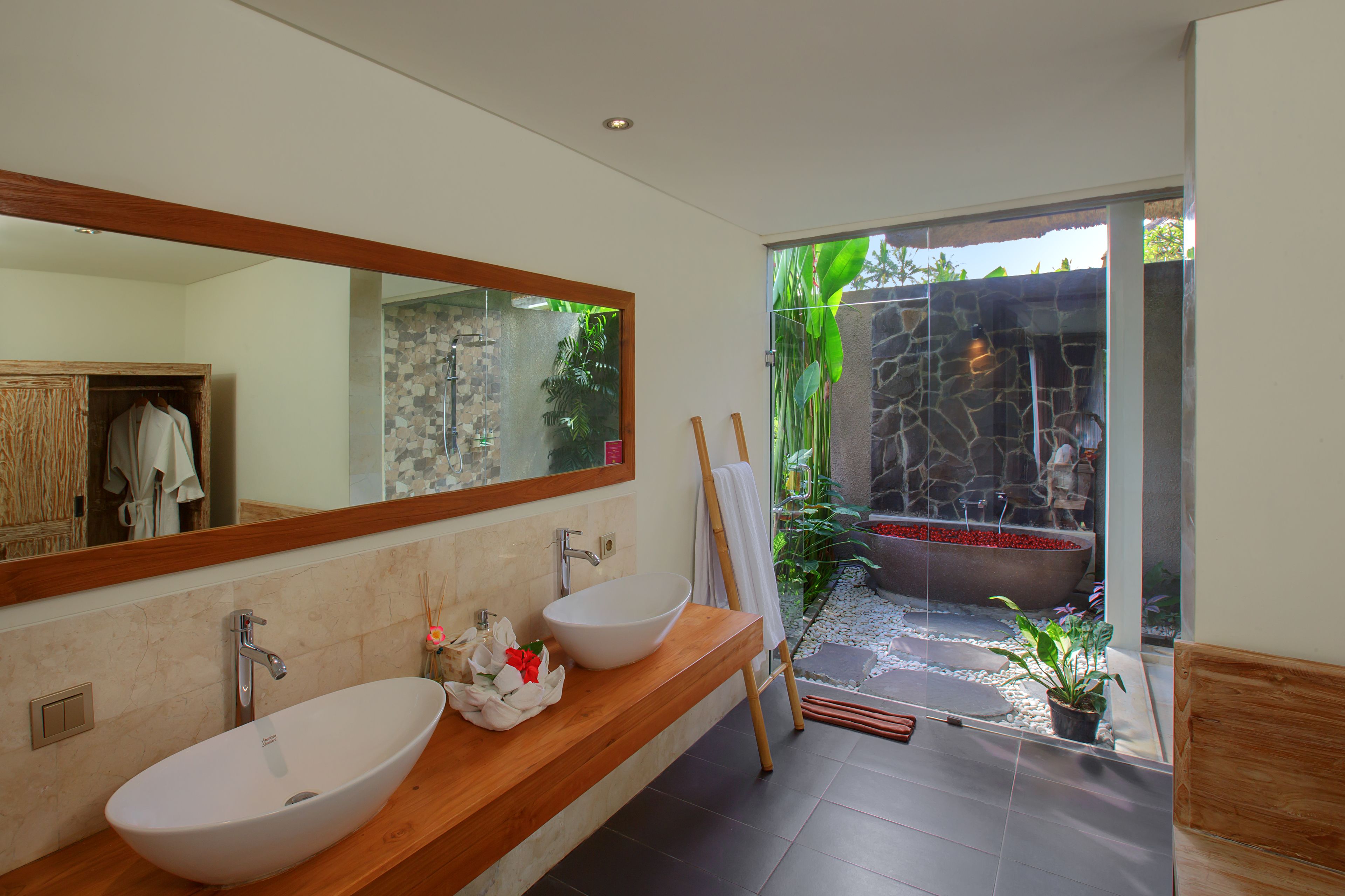 A modern bathroom with a large mirror, two sinks, and a stone wall.