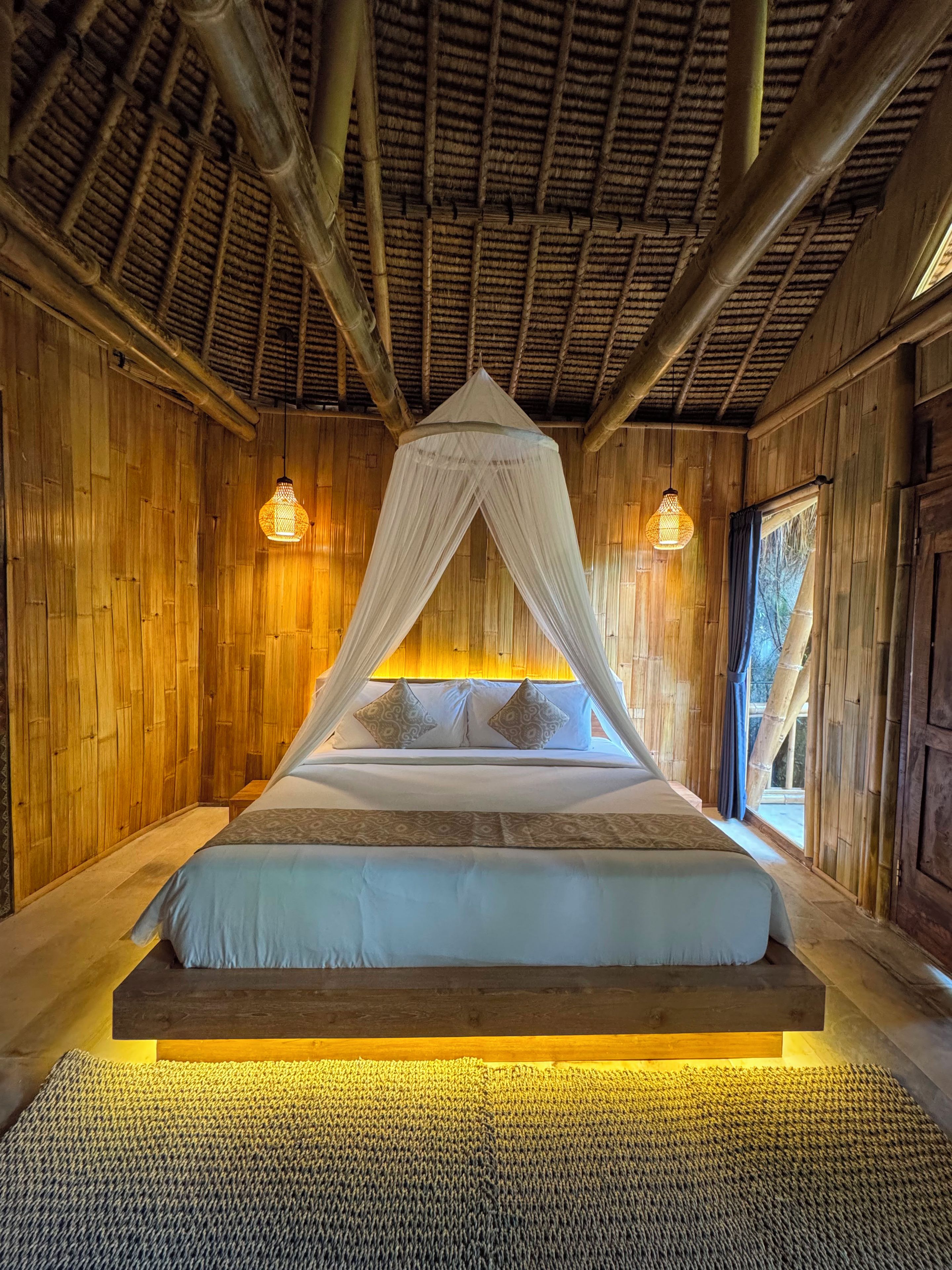 A bed with a canopy, wooden walls, and a thatched roof.