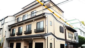Um edifício com vários andares, fachada bege, janelas emolduradas a preto e varandas.
