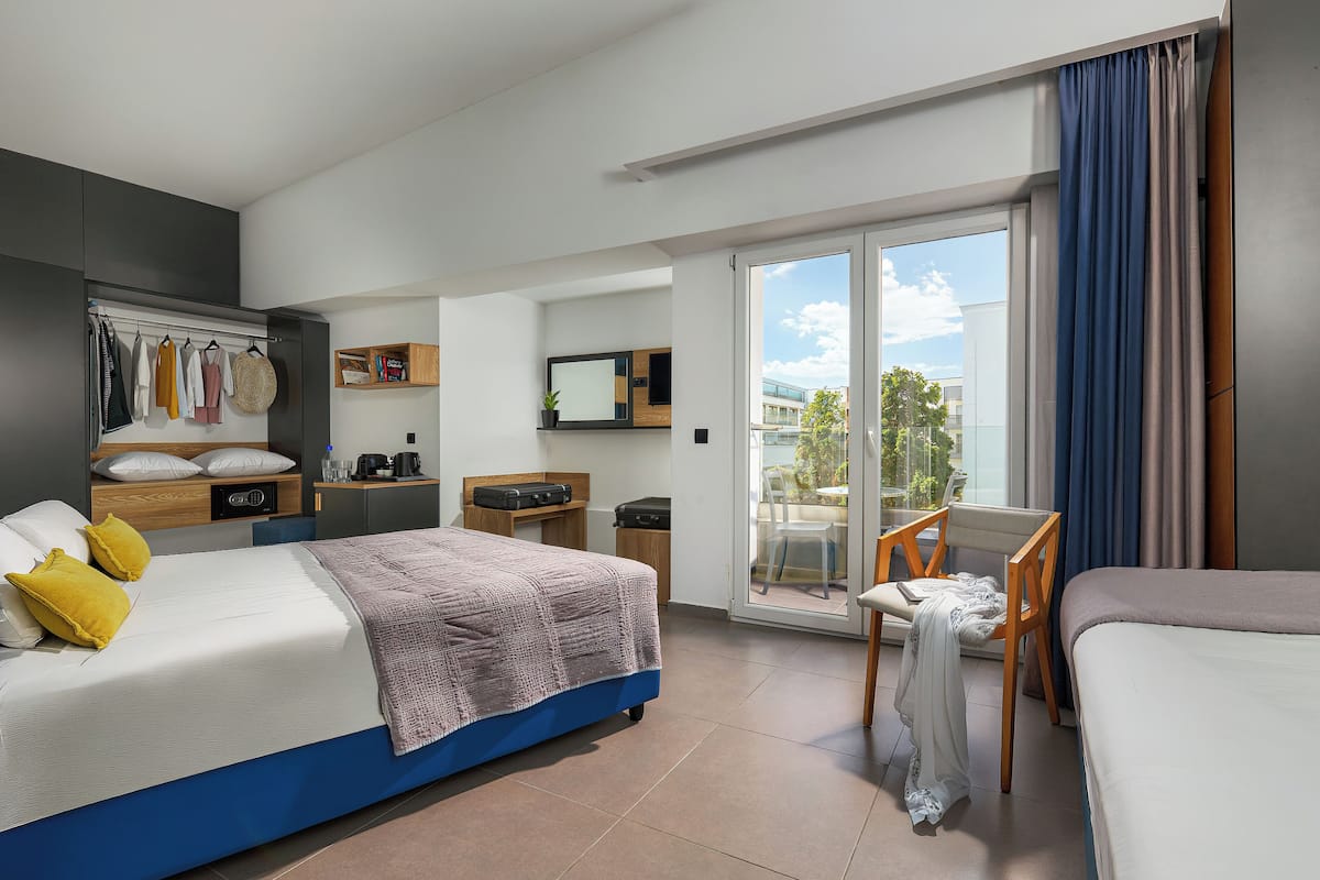 Ein modernes Hotelzimmer mit einem großen Bett, einem Schreibtisch, einem Sessel und einem Balkon mit Blick.