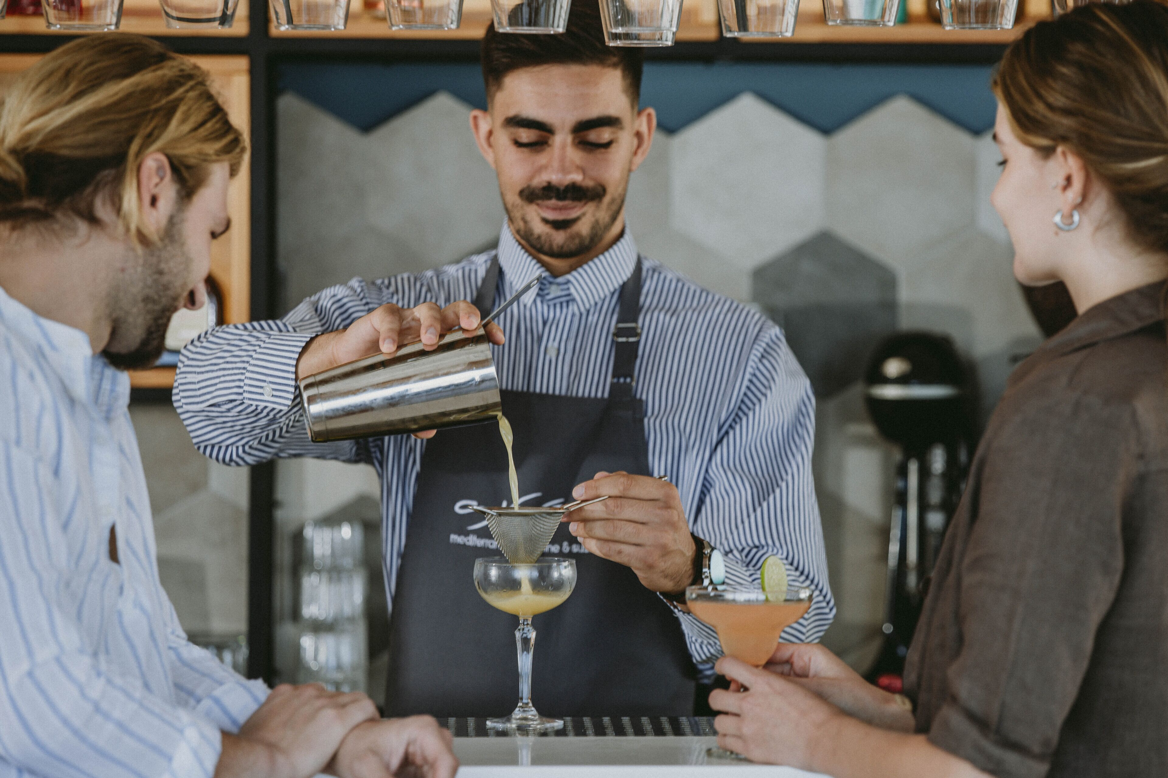 A bartender pouring a drink into a glass.