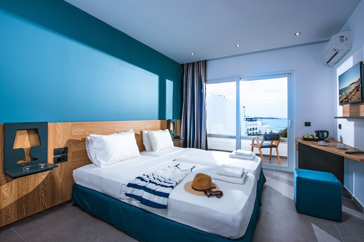 Ein modernes Hotelzimmer mit einem großen Bett, einem Schreibtisch und Meerblick.