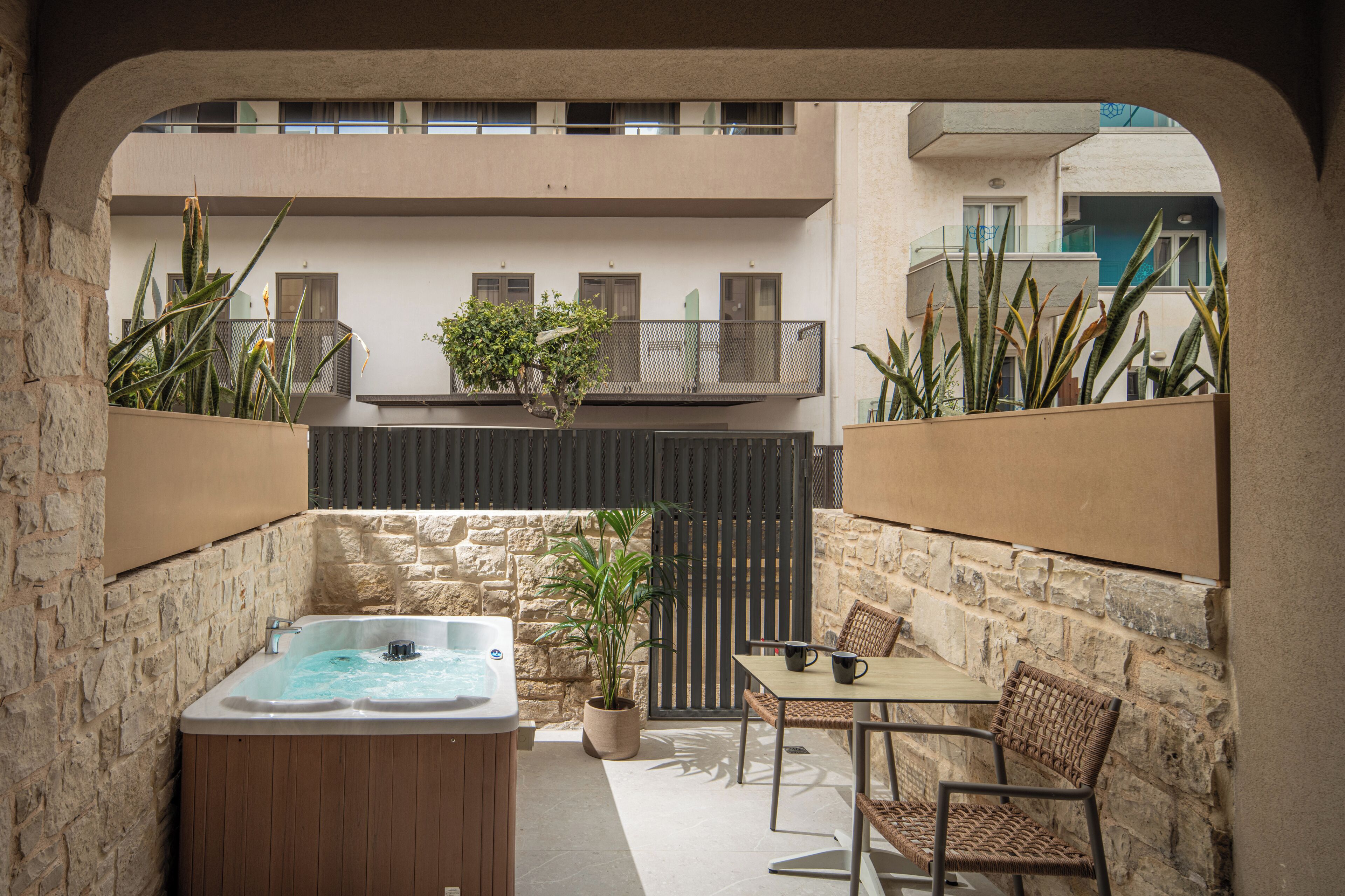 A spa area with a hot tub, seating, and potted plants.