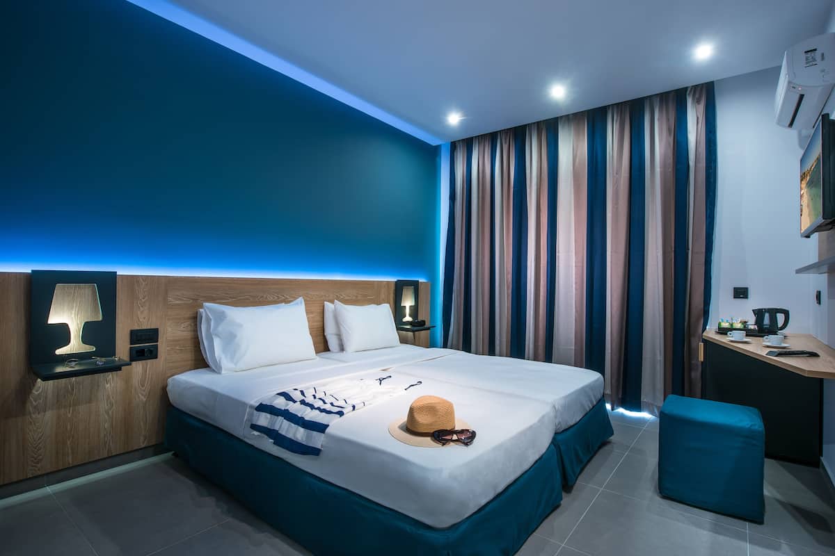 Ein modernes Hotelzimmer mit einem großen Bett, Nachttischlampen, einem Schreibtisch und einem Streifenmuster-Vorhang.