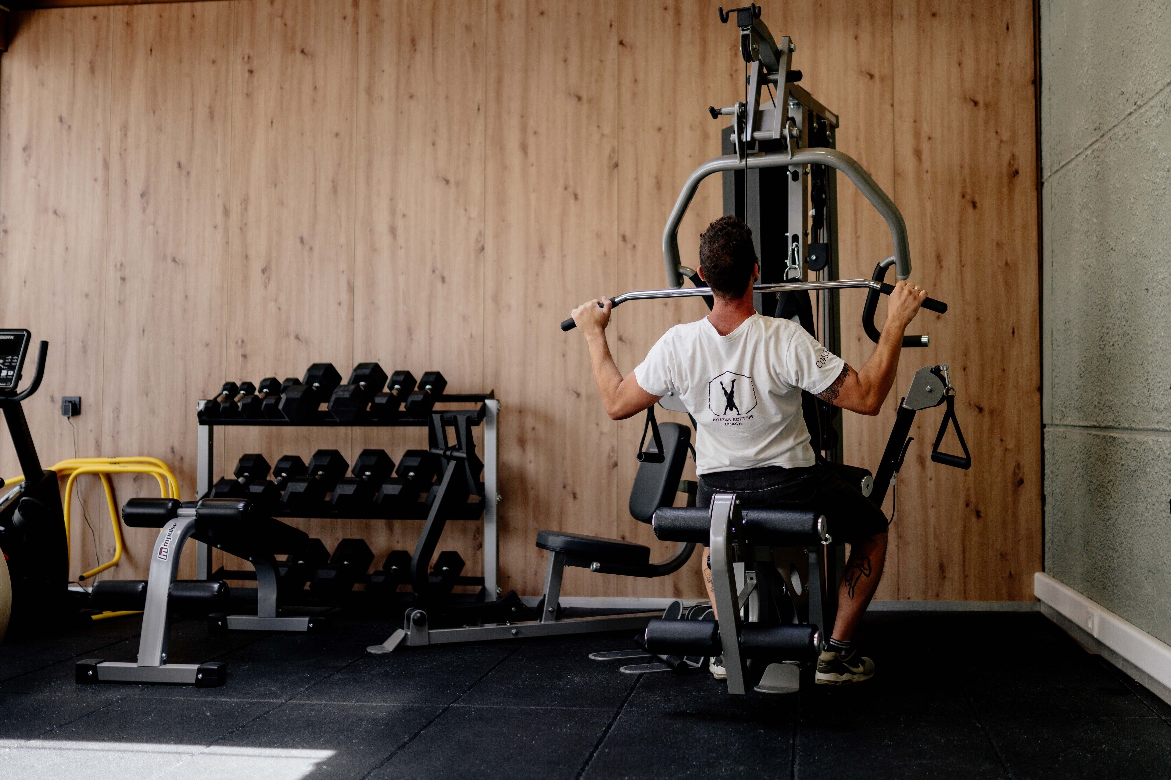 Une salle de sport avec un mur en bois, un banc de développé couché, des haltères et un support à squats.