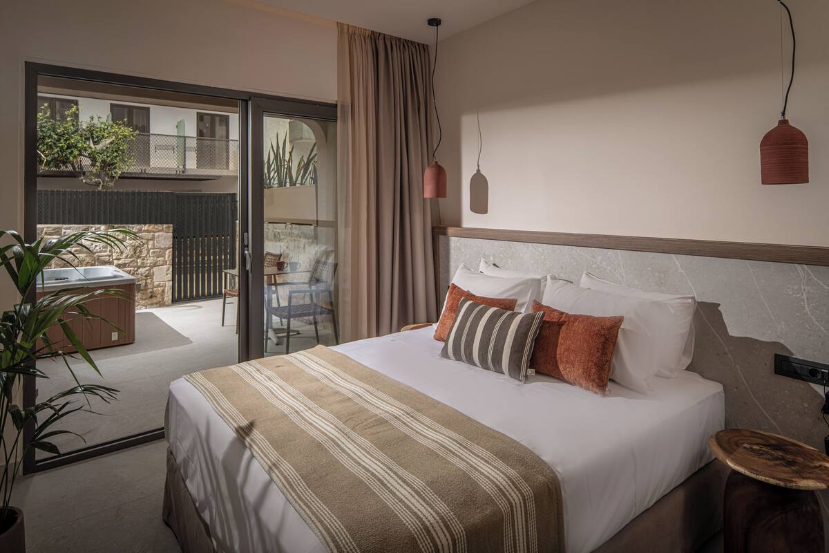 Ein Hotelzimmer mit Bett, Nachttisch, einer Pendelleuchte und Blick auf den Balkon.