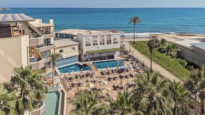 Een hotel met een zwembad op het dak, uitzicht op het strand en een loungeruimte bij het zwembad.
