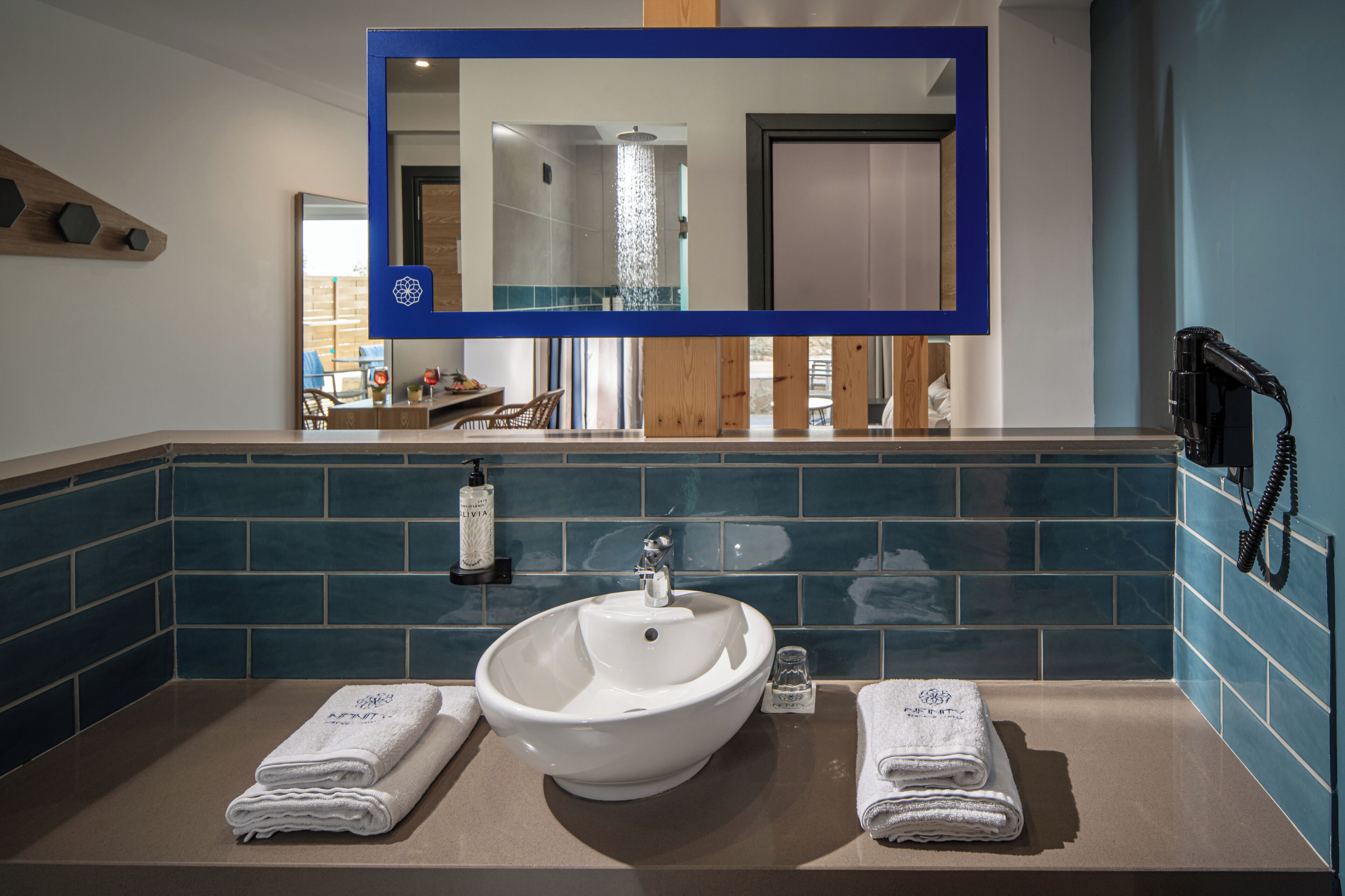 A bathroom with a large mirror, a sink, two towels, a bottle of hand soap, and a telephone.