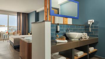 Un baño moderno con un espejo grande, un lavabo y un secador de pelo. Hay una ventana con cortinas y vistas al exterior.